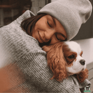 Cavalier King Charles in den Armen seiner Halterin, die ihn vernünftig mit einer Hunderversicherung abgesichert hat Hundehalterin hält ihren Hund liebevoll im Arm, Vorauf sollte man vor der Anschaffung eines Cavalier King Charles achten